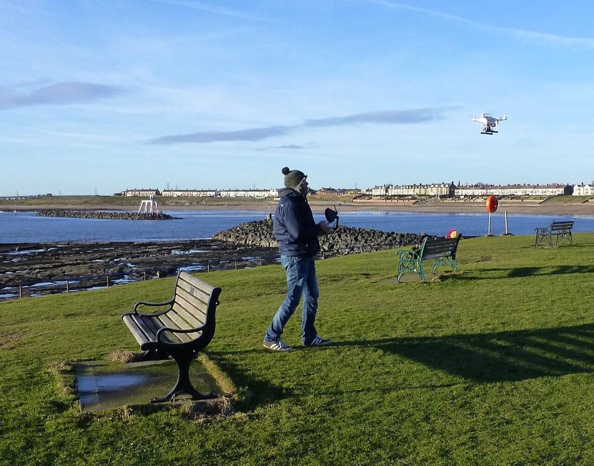 Una persona pilota un dron junto al mar